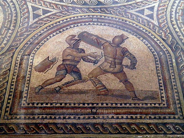 Roman gladiators depicted in a mosiac discovered in Germany. The gladiator on the left wields a sica the curved dagger which gave its name to the Sicarii. Photo courtesy of Wikimedia Commons.