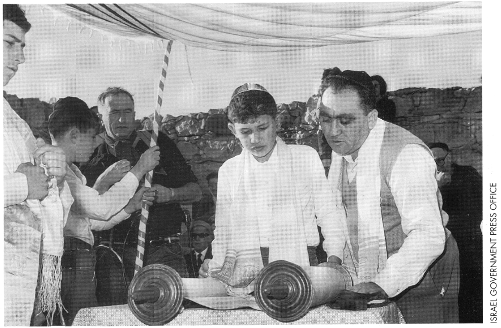 An Israeli boy reading from a Torah scroll during his Bar Mitzvah ceremony held in the ruins of the ancient synagogue at Masada (Jan. 1967).
