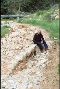 Tour group member sitting on one of the curbing stones that has been revealed by the erosion. Photographed by Lucinda Dale-Thomas, spring 1992.