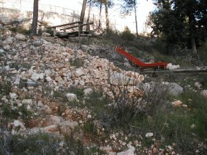 The remains of a red slide, part of the play equipment in the former KKL park. The rubble ran down the slopes of the cemetery and destroyed the park before the wall and fence were erected by cemetery authorities. Photographed by David Bivin.